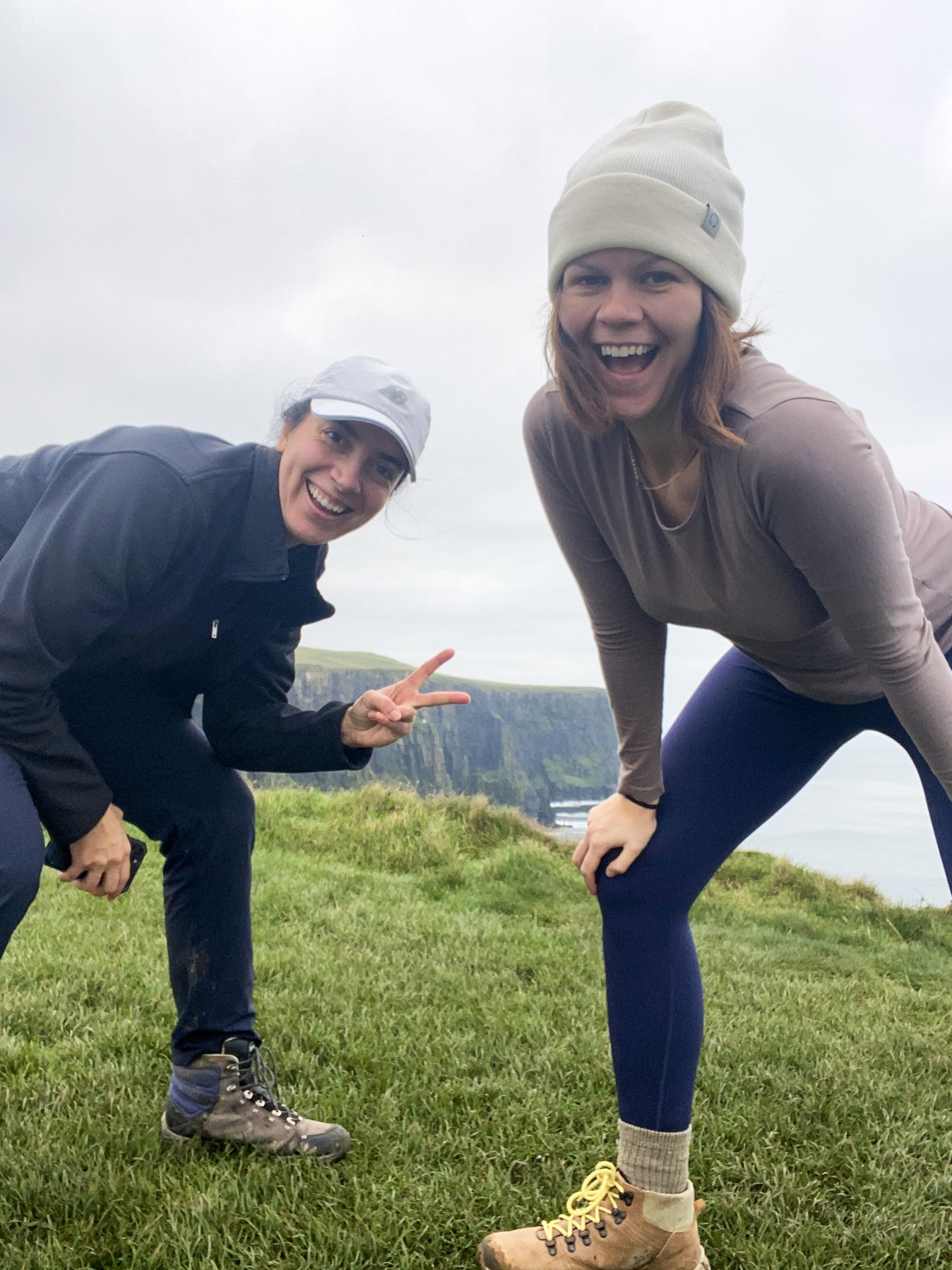 two girls hiking the cliffs of moher coastal path smiling for a photo
