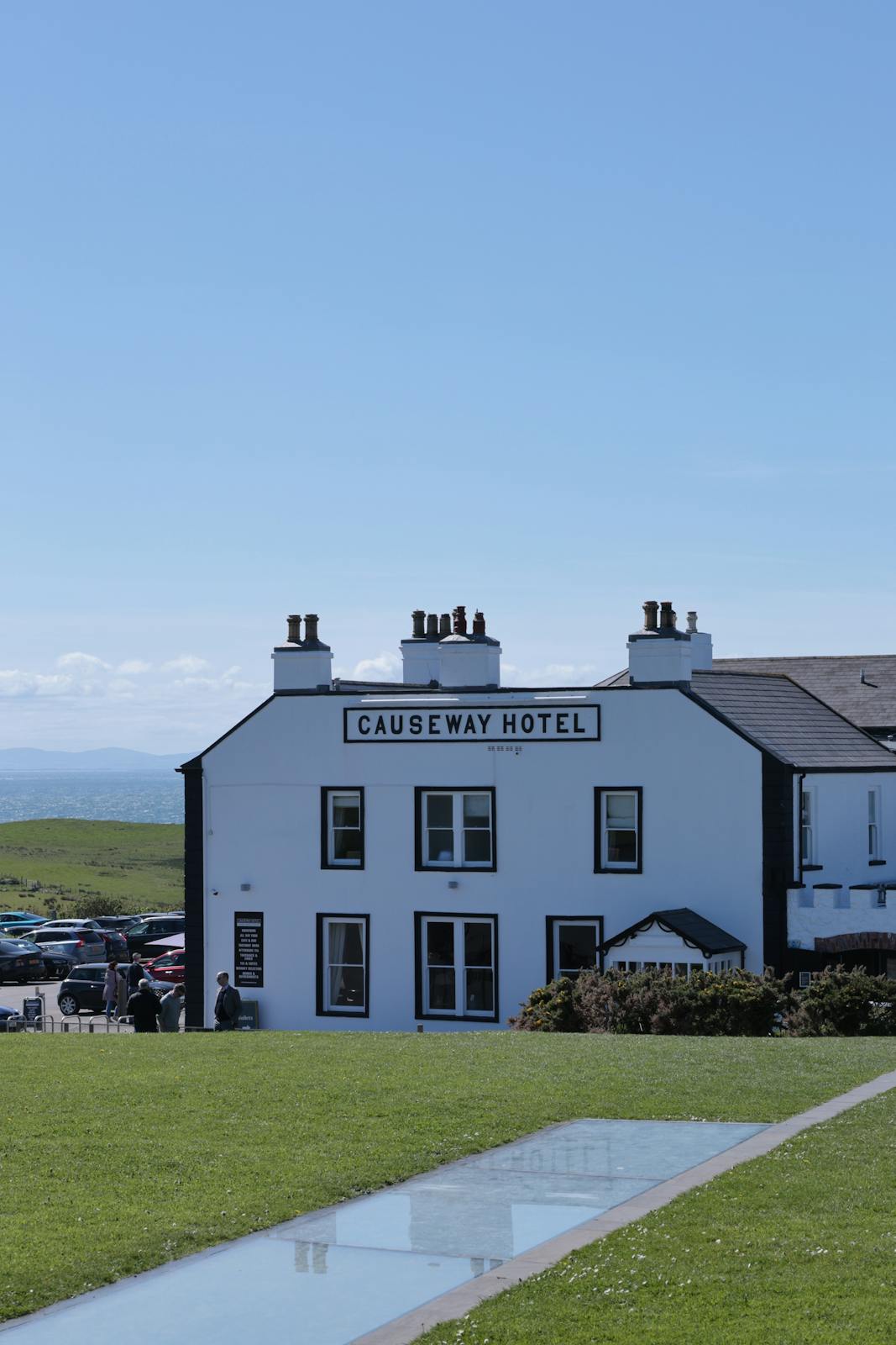 Facade of the Causeway Hotel with grassy surroundings on a sunny day.