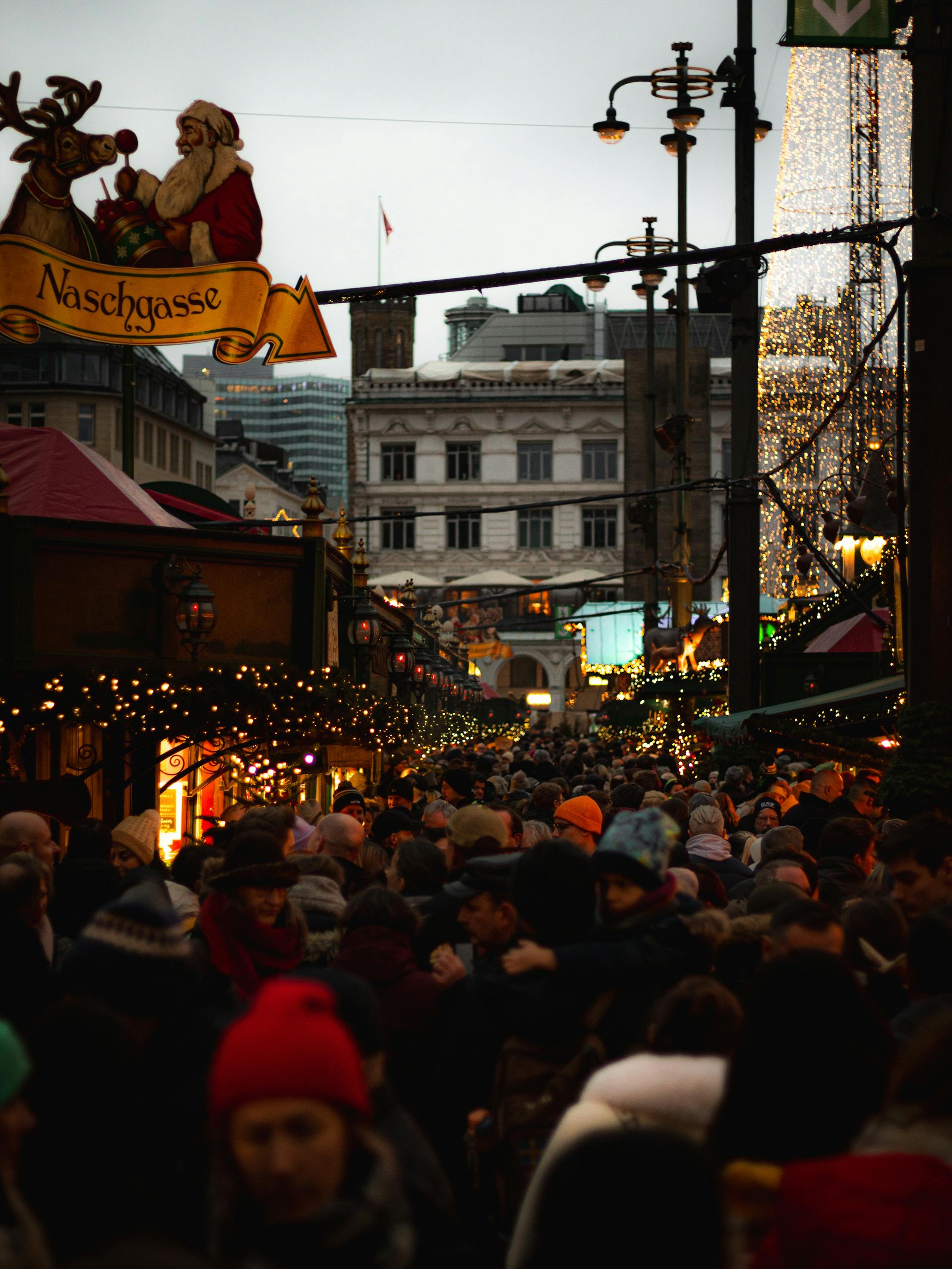 Festive atmosphere at a bustling Christmas market in Hamburg, Germany captured at twilight.