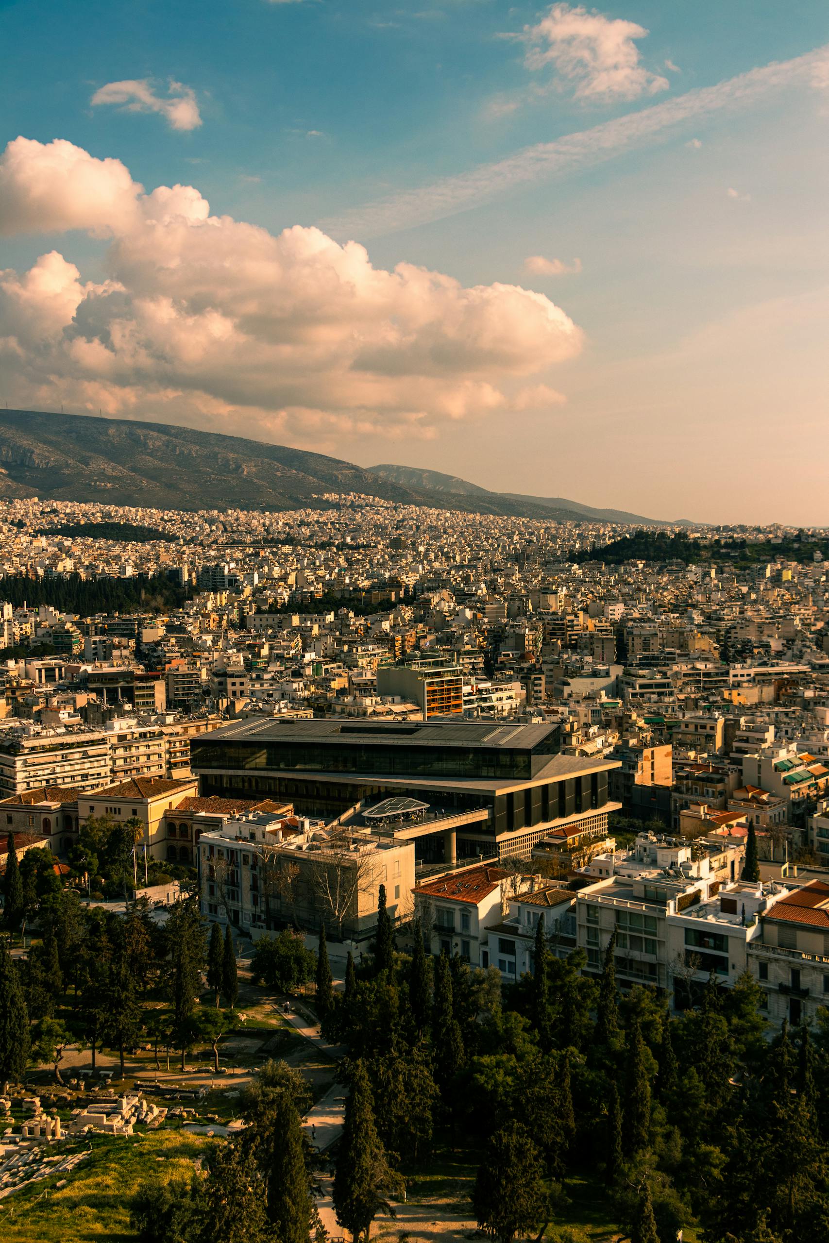 Scenic aerial view of Athens featuring the Acropolis Museum and cityscape under a cloudy sky in 2025
