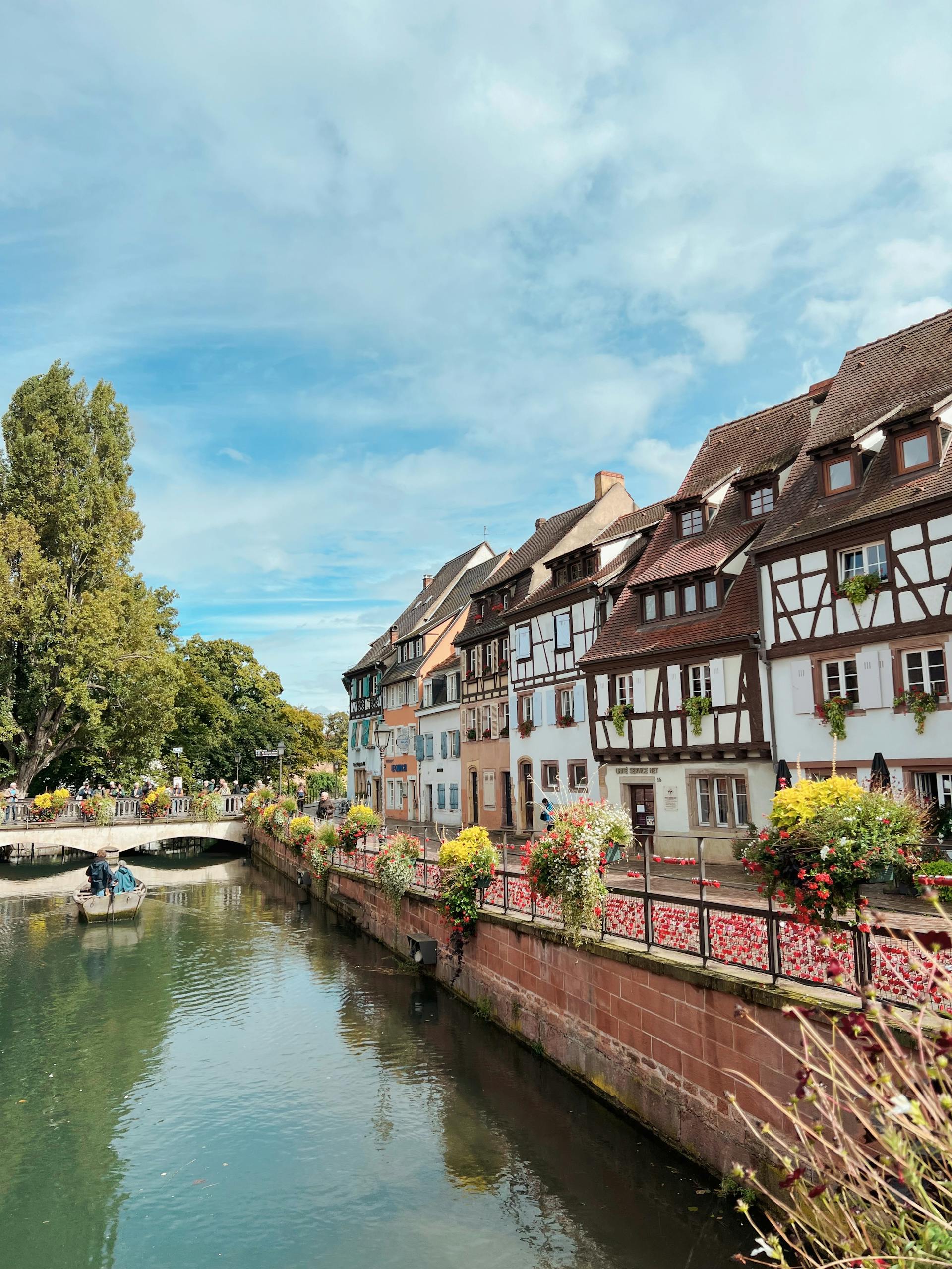 Charming historic European town with canal and timbered houses under a blue sky.