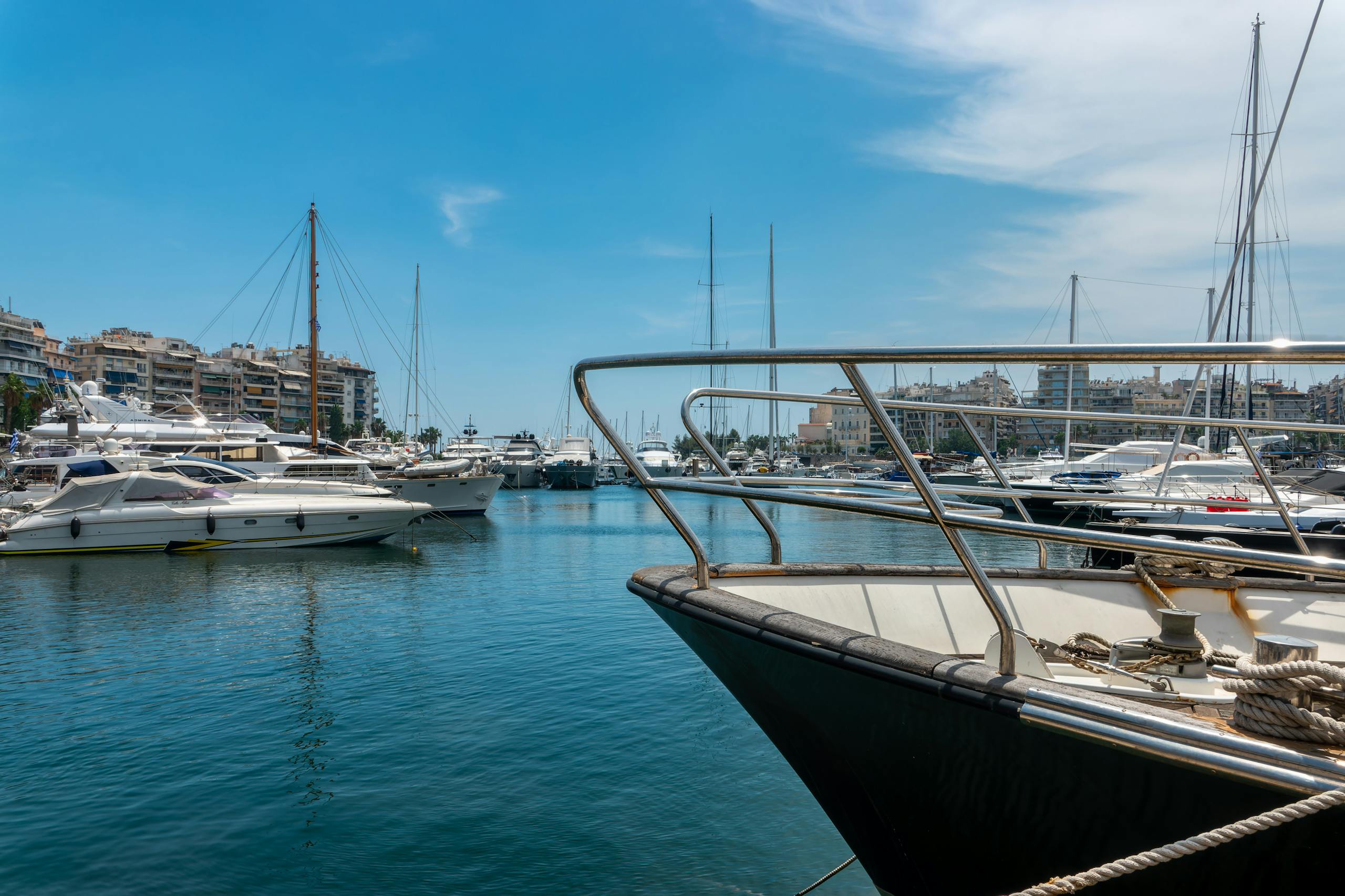 Scenic view of luxury yachts docked at Piraeus Marina in Greece under a clear blue sky.
