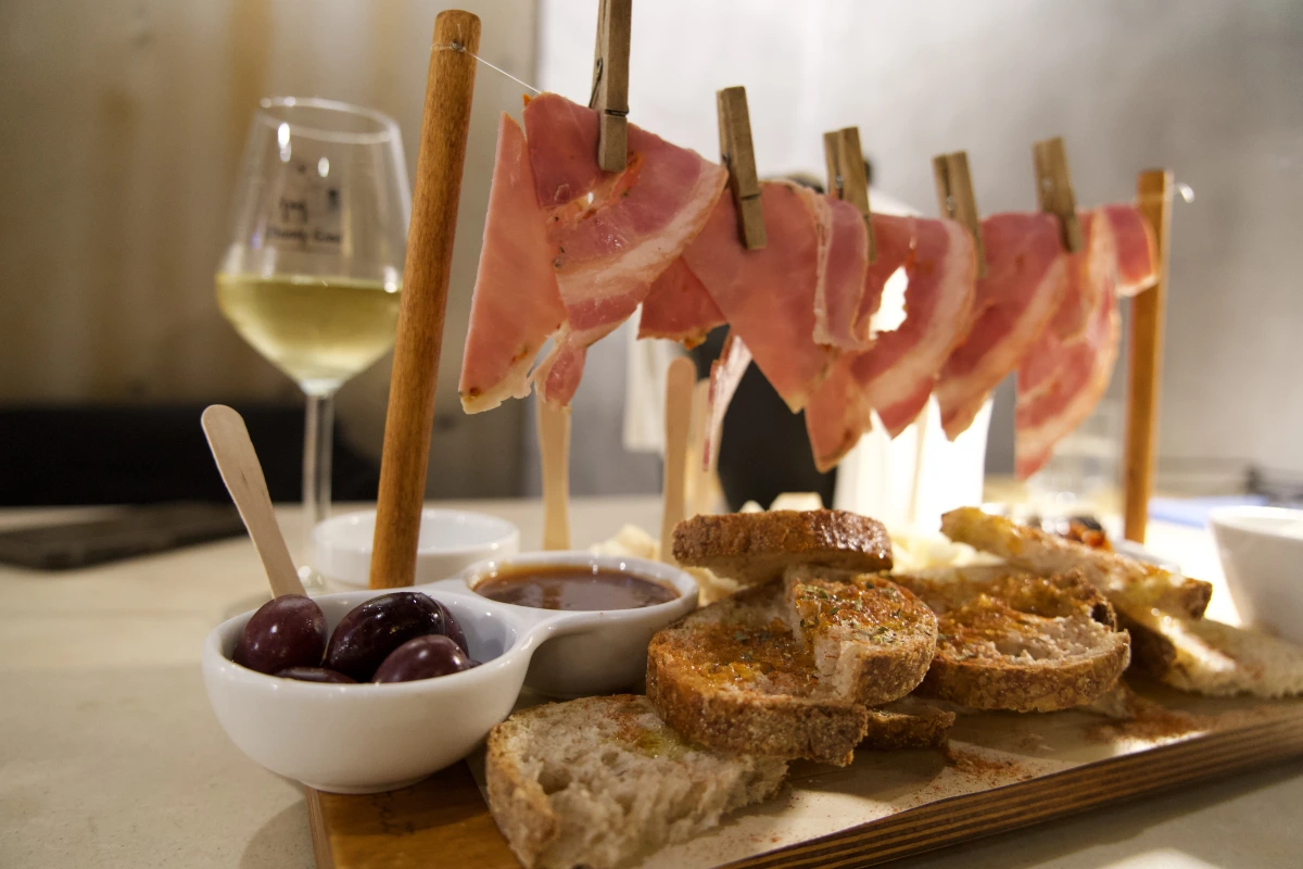 a glass of wine with a meat and wine plate at the drunky goat wine bar in athens