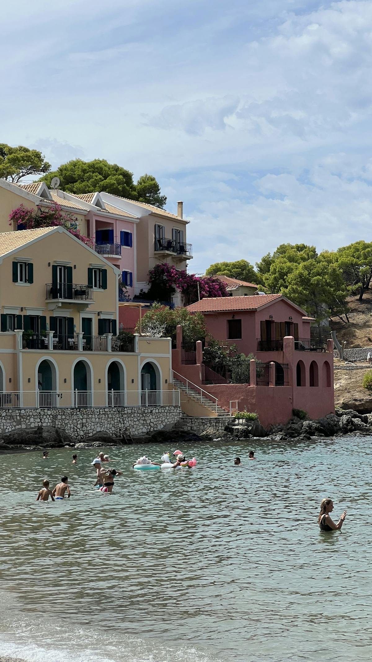 Charming seaside village with colorful houses by the beach, people enjoying summer waters.