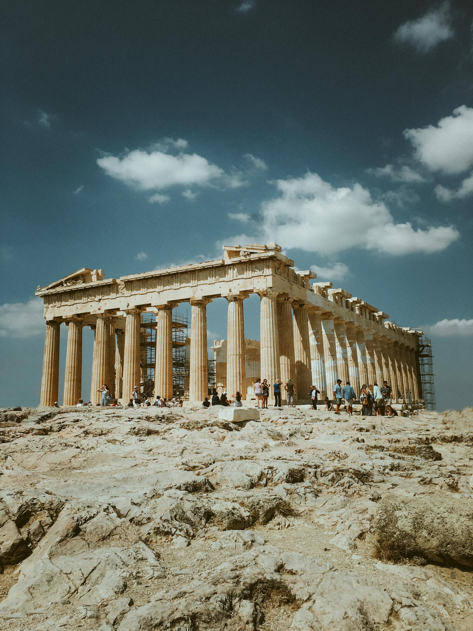 Low angle shot of the Parthenon, Athens, with tourists against a clear blue sky.