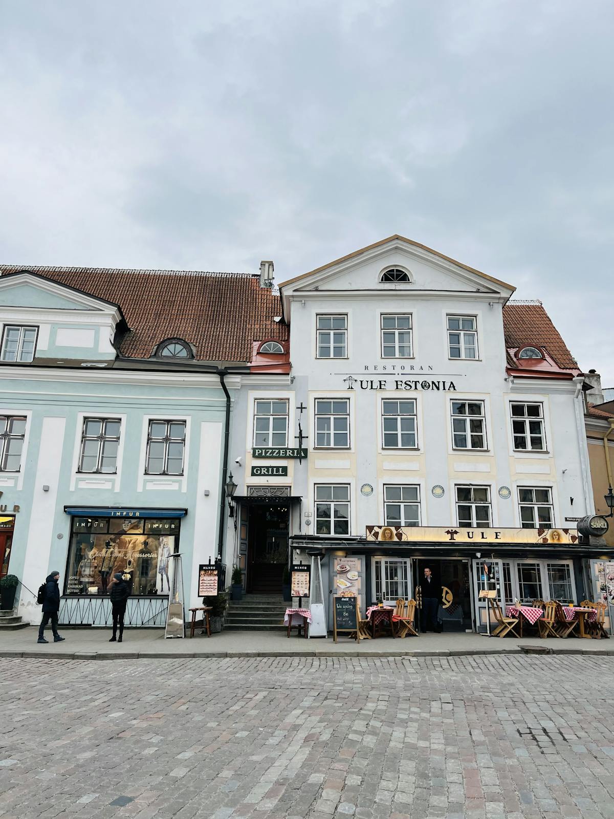Scenic view of historic Tallinn street with colorful buildings and local eateries.