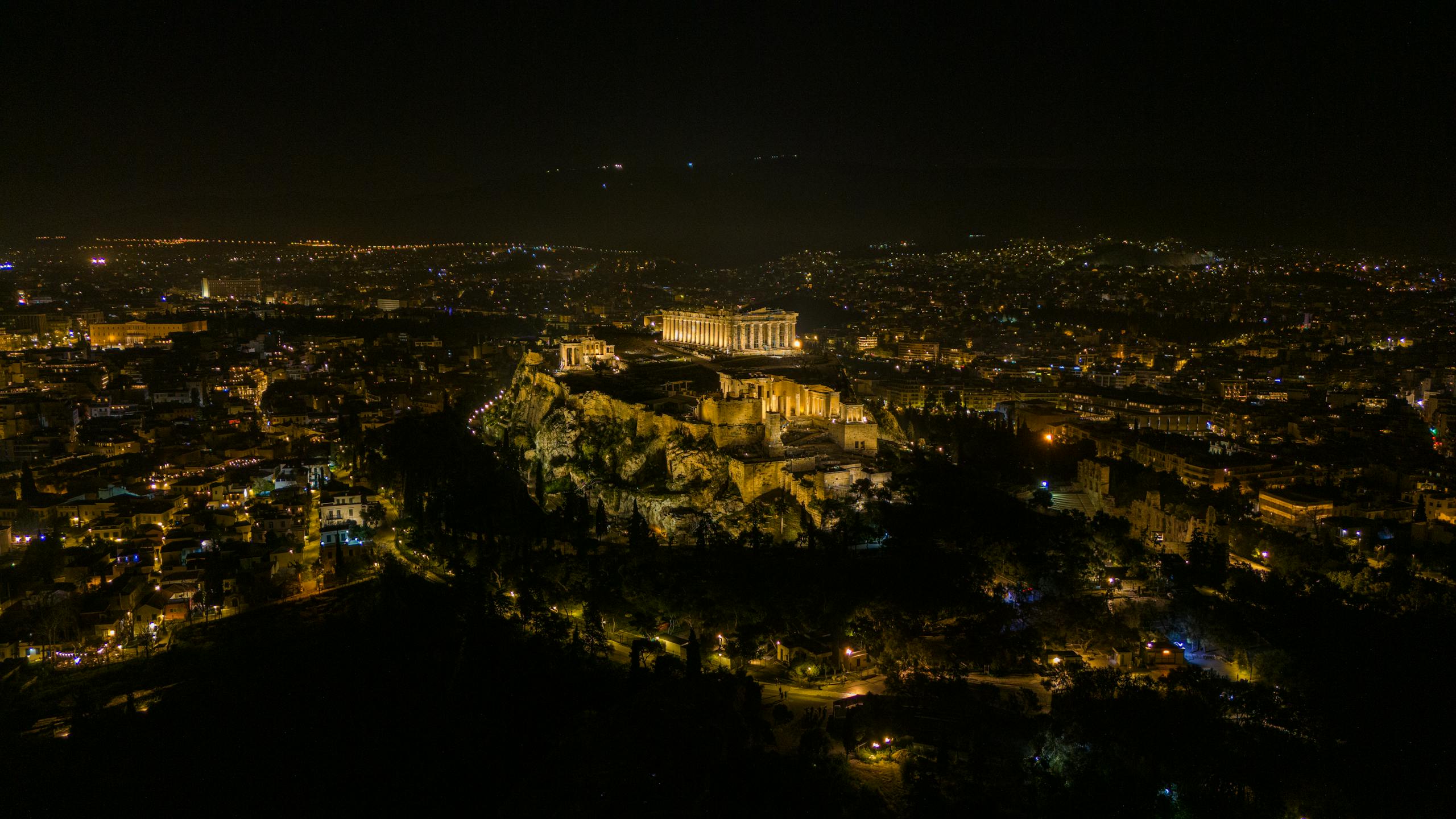 Stunning aerial view of the illuminated Acropolis and Parthenon at night in Athens, Greece.