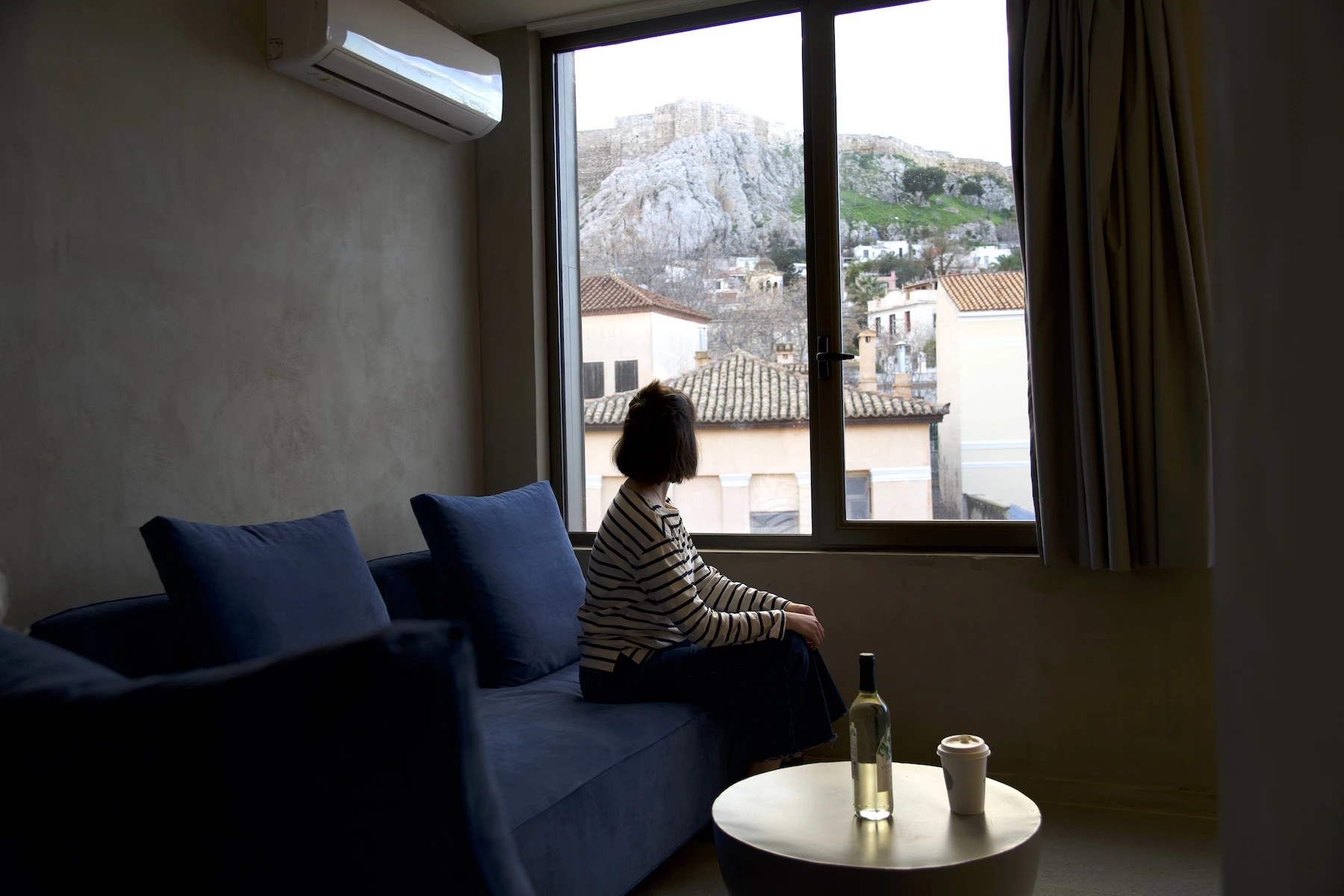 girl looking at the acropolis in athens through hotel window