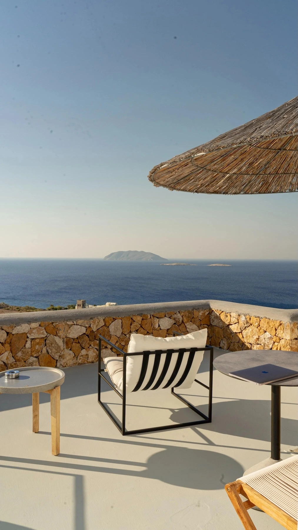 Scenic Greek island coastline view from hotel patio with a comfy chair overlooking the sea