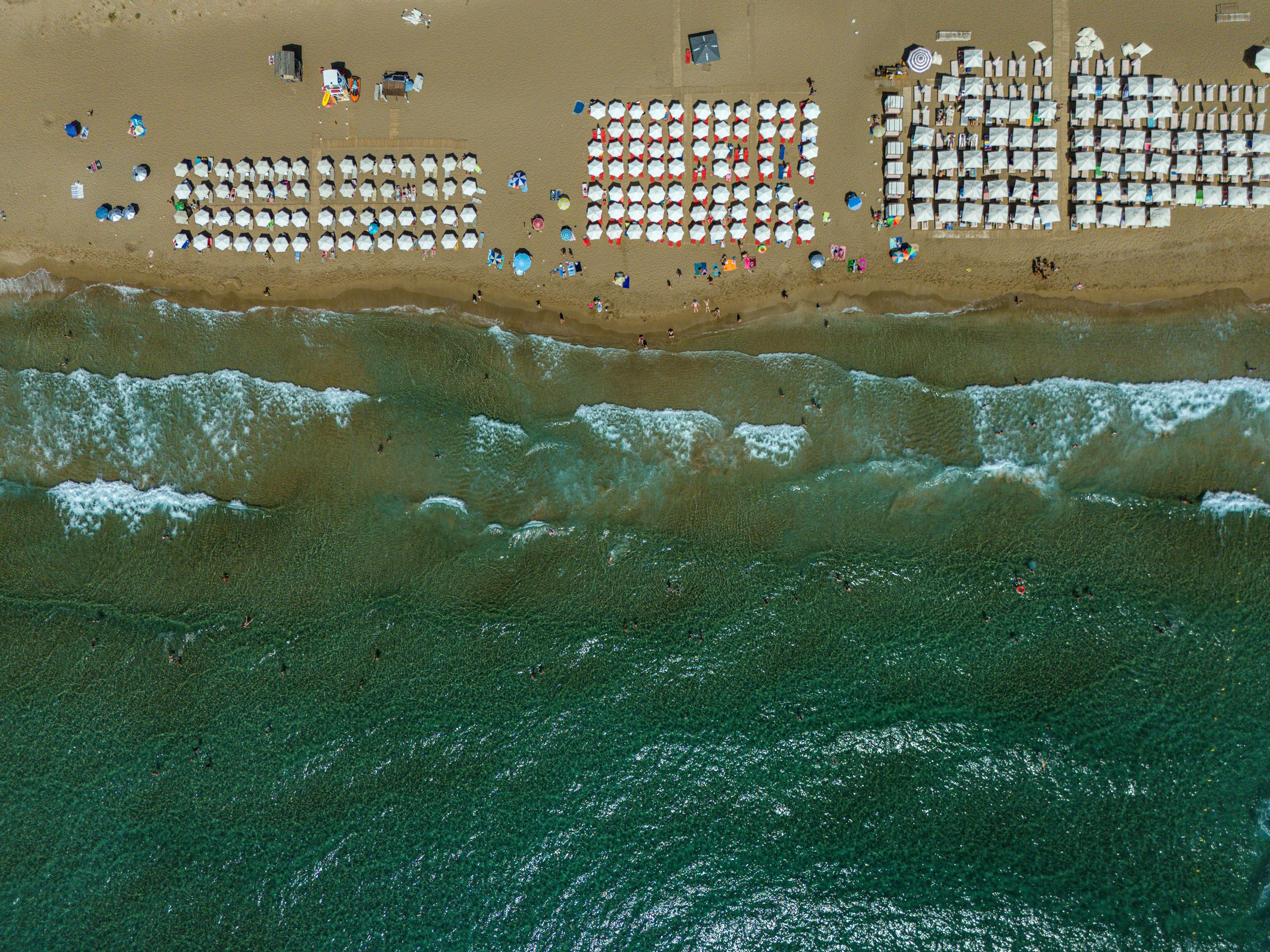 Beautiful aerial view of Glyfada Beach in Greece with waves and sunbathers.